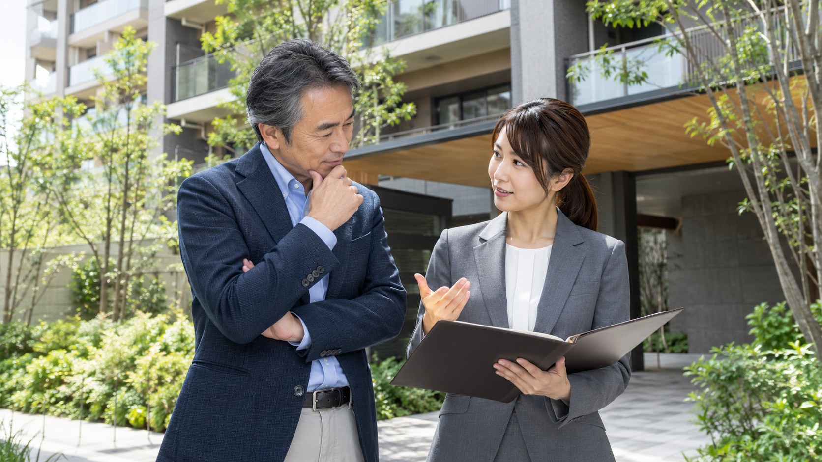 建物前の庭で資料を手に話す男性オーナーと女性担当者